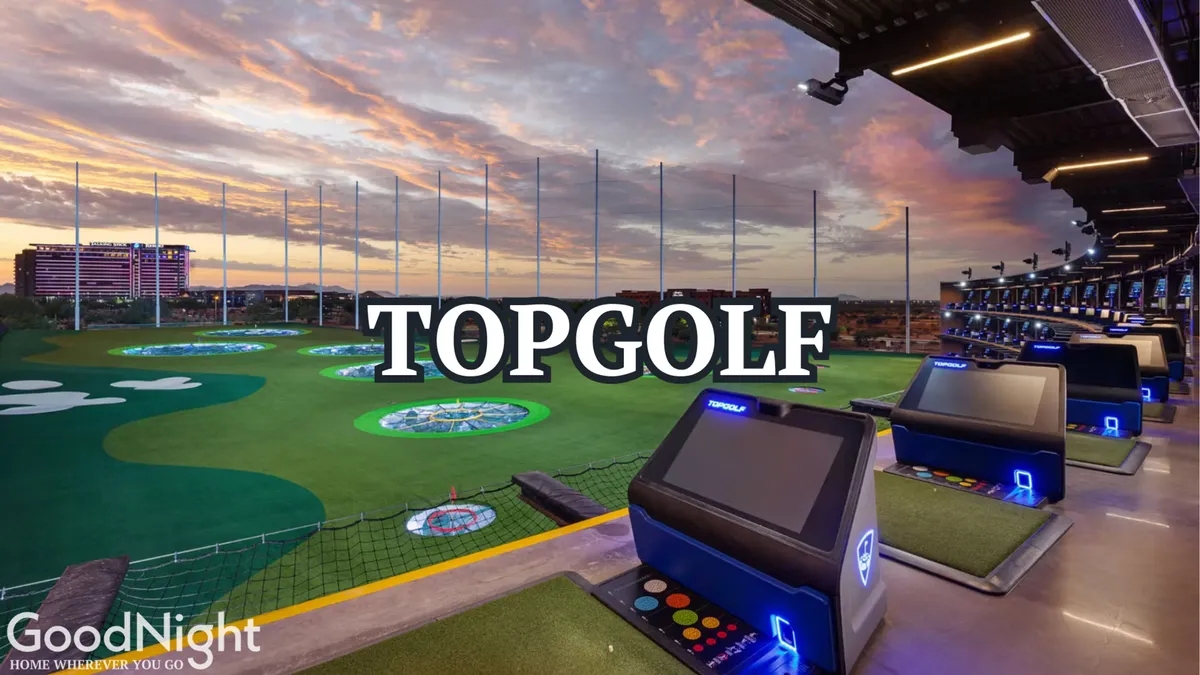 Topgolf’s dynamic golfing bays overlook a field dotted with colorful targets, set under a sky painted with sunset hues. Social groups can be seen enjoying the game, with food and drinks in hand, creating a lively, playful atmosphere.