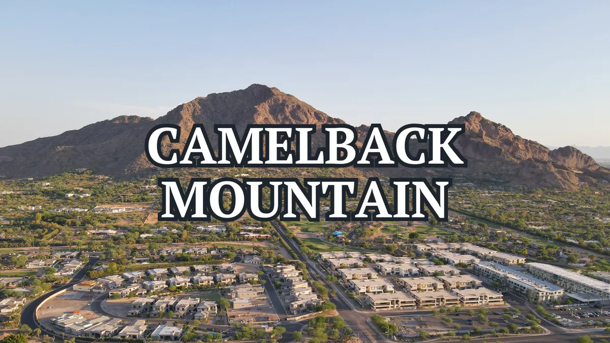 Camelback Mountain rises majestically above the surrounding residential area, its rugged silhouette illuminated by the soft glow of sunrise. The scene suggests easy access to hiking trails and outdoor adventures within minutes from home.